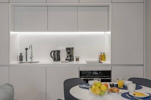 A modern kitchen with a built-in sink, a coffee maker, and a dining area with a table set for breakfast.