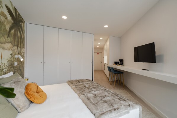 Une chambre d’hôtel moderne équipée d’un lit, d’un bureau et d’une télévision.