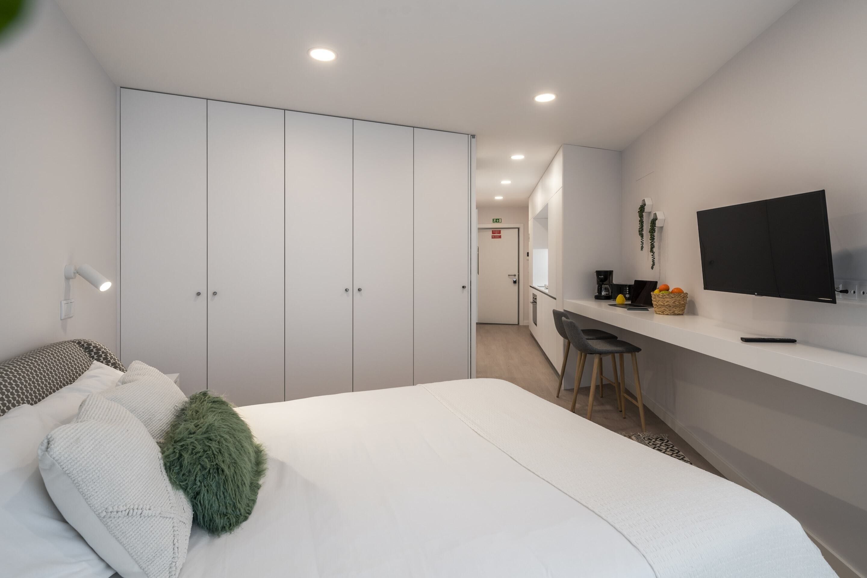 A modern hotel room with a bed, a desk, and a TV.