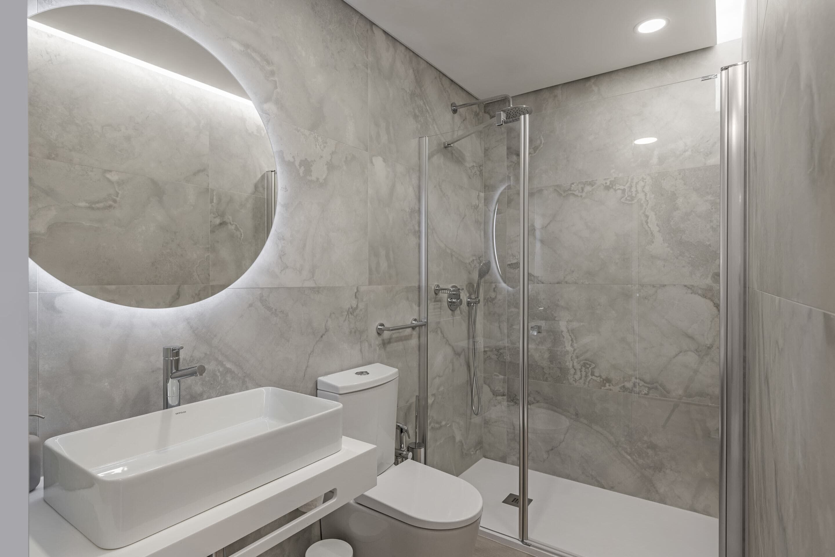 Un bagno moderno con un lavandino capiente, un water e un box doccia in vetro.