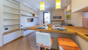 Cocina moderna con encimeras de madera, horno integrado y comedor con banco y mesa.
