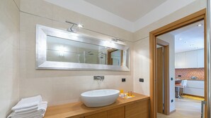 Un baño moderno con un espejo grande, un lavabo blanco y toallas ordenadas sobre el mueble.