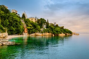 A coastal town with buildings on a hillside overlooking a calm sea. - Pool And Garden Apartment Happy Sound (Rijeka)