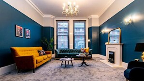 Uma sala de estar com um sofá amarelo, um sofá verde e uma lareira.