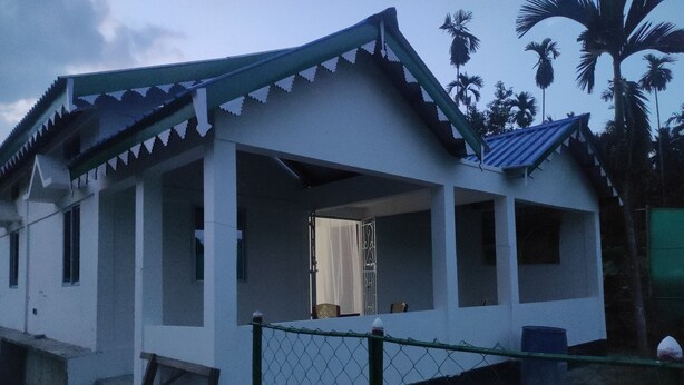 Uma casa branca com telhado pontiagudo e varanda.
