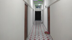Um corredor estreito com piso estampado, teto verde e roxo, e uma porta no final.