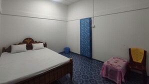 Quarto com cama, uma cadeira, parede azul e ventilador de teto.