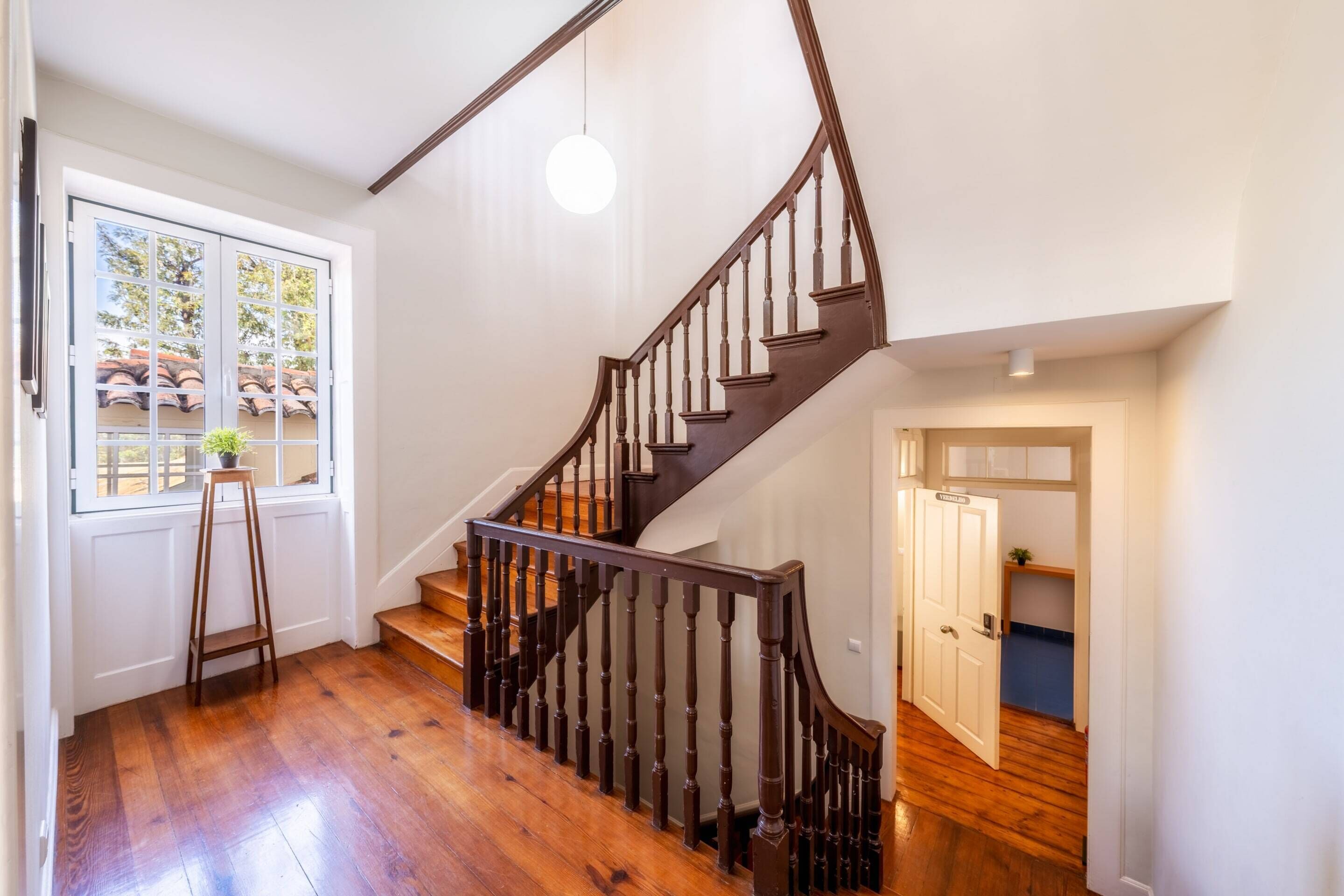 A wooden staircase with a dark handrail and a white door at the bottom.
