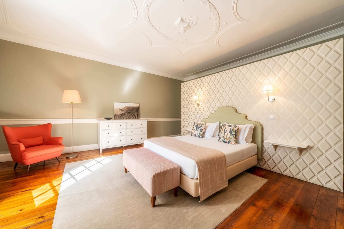 A bedroom with a bed, a chair, a dresser, and a lamp.