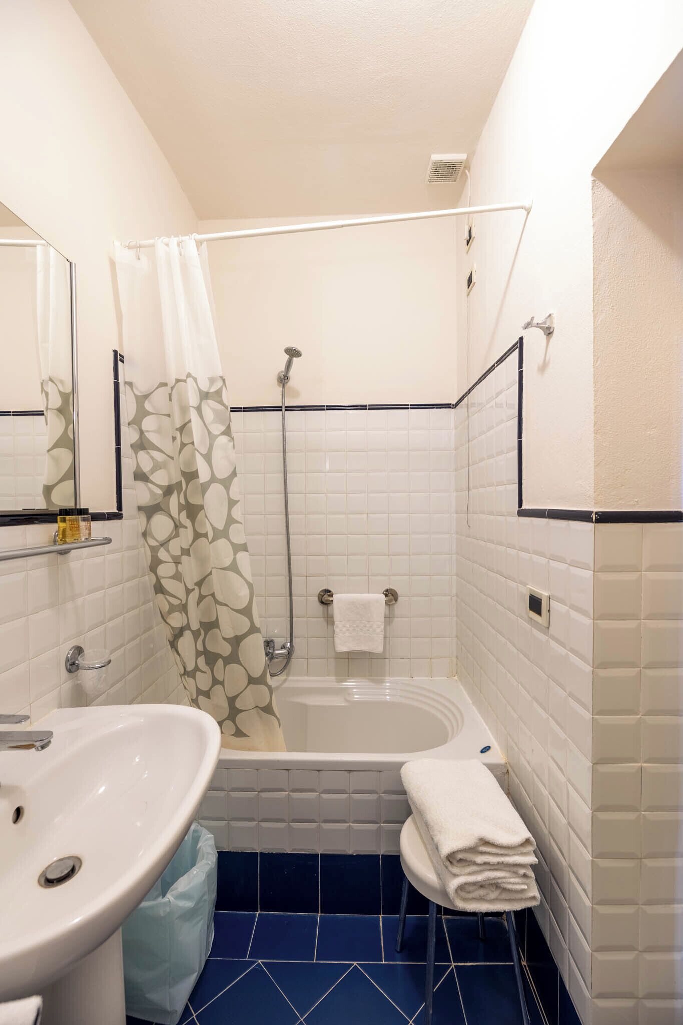 Un baño con bañera, ducha, lavamanos y toallero.
