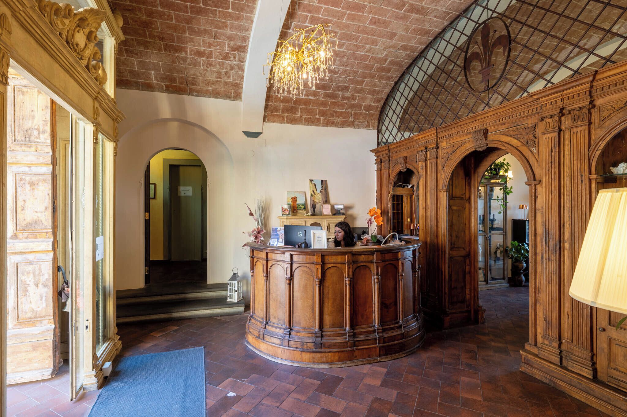 A lobby with a wooden reception desk, arched doorways, and a tiled ceiling.