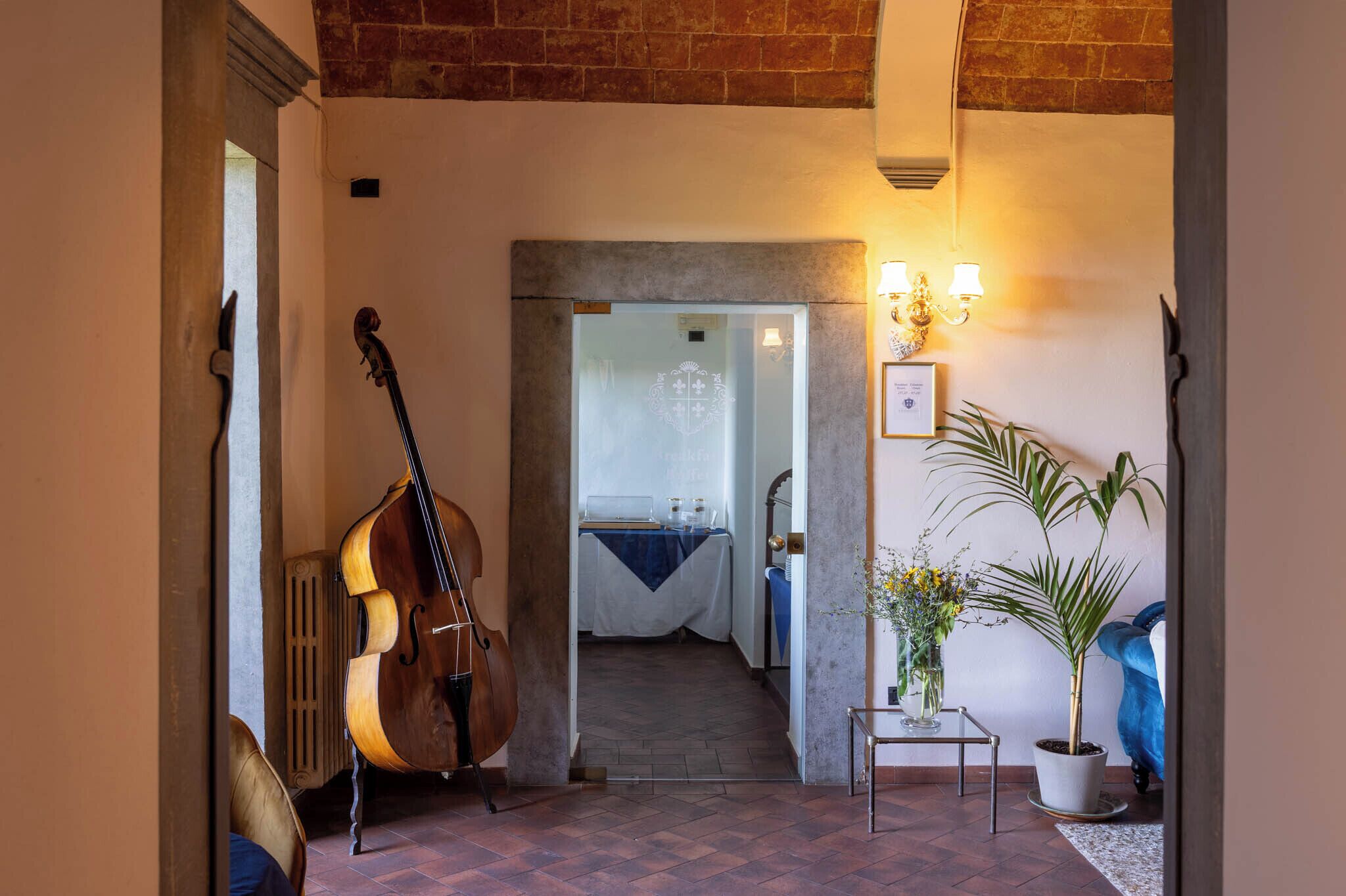 A hallway with a grand piano, a potted plant, and a framed certificate on the wall.