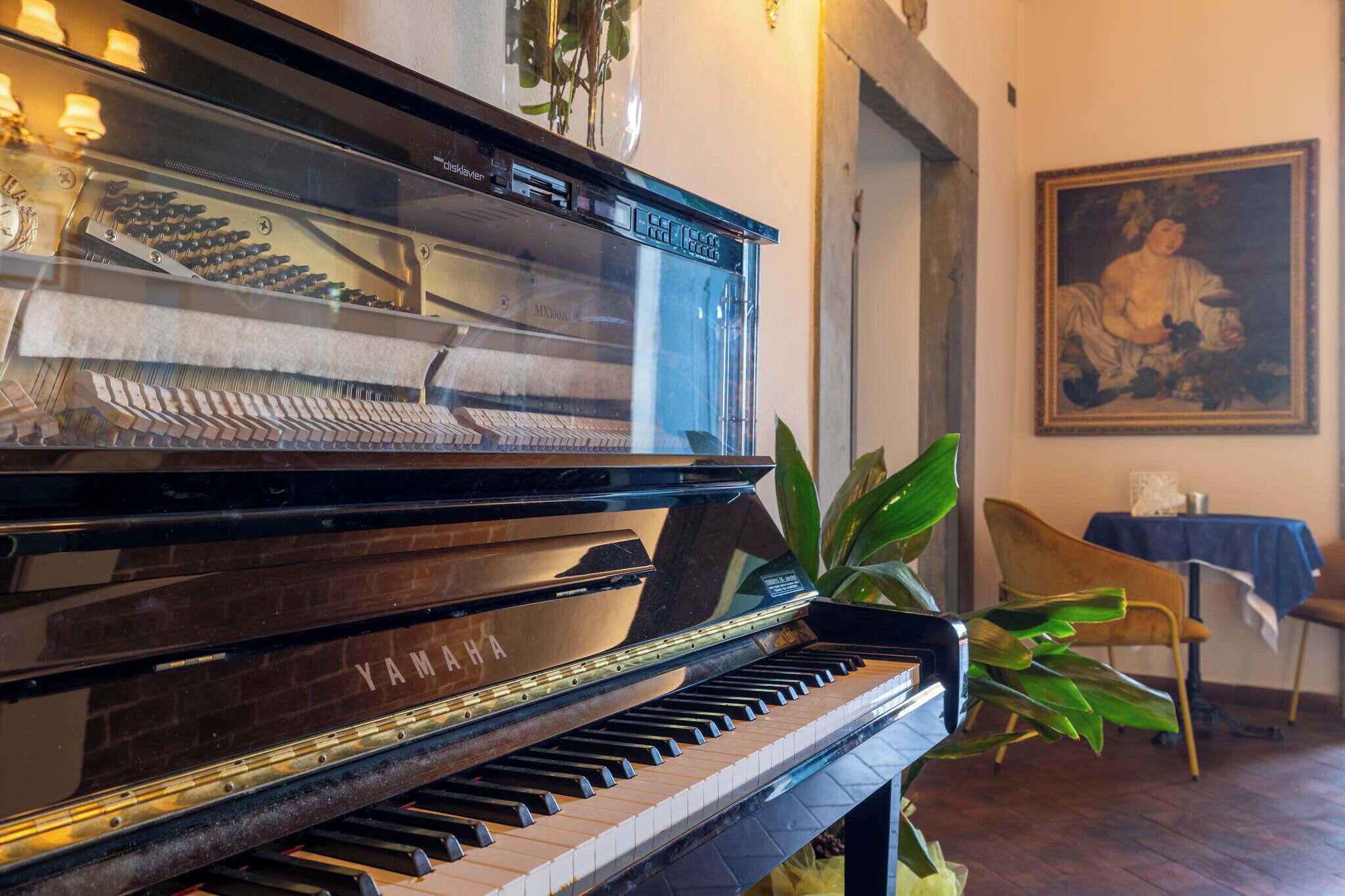 A grand piano, a chair, a table, and a framed painting in a room.