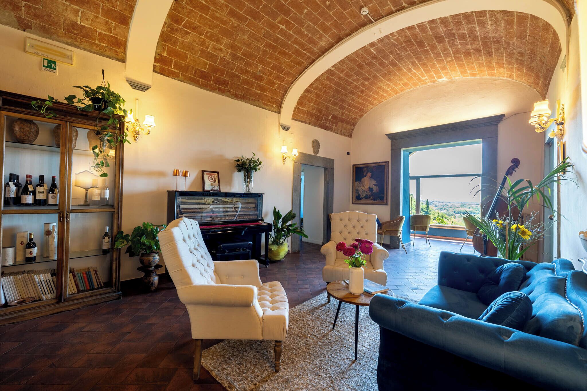 A spacious living room with a grand piano, a bookshelf, and a blue sofa.