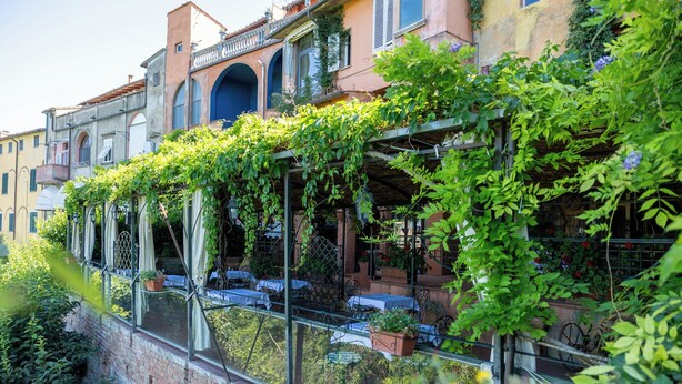 A building with a brick facade, arched windows, and a balcony with tables and chairs. - Quattro Gigli Palace (Montopoli in Val d'Arno)