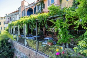 A building with a brick facade, arched windows, and a balcony with tables and chairs. - Quattro Gigli Palace (Montopoli in Val d'Arno)