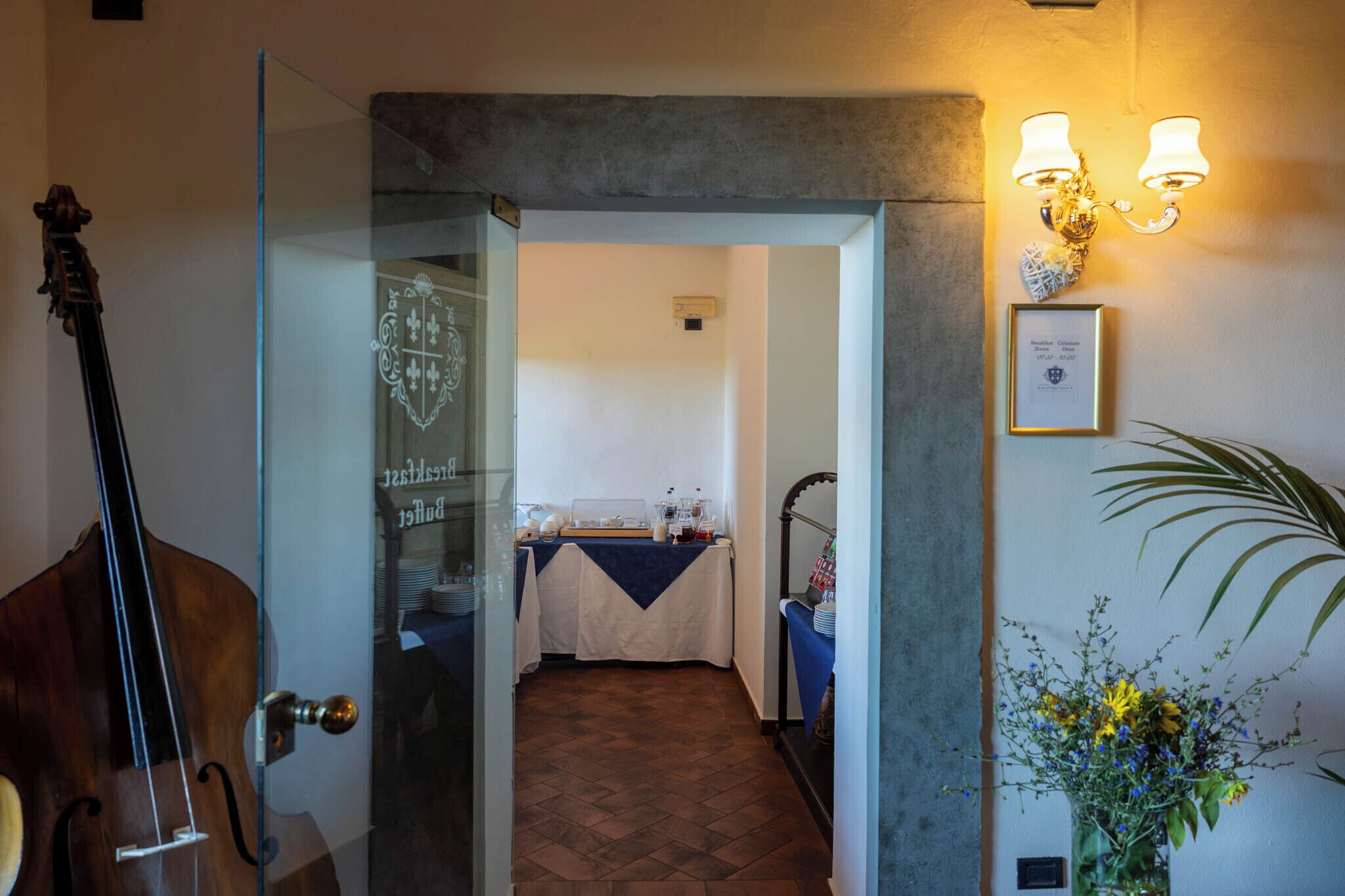Una stanza con una porta in vetro che dà su un'area pranzo, un lampadario a parete e un certificato incorniciato appeso al muro.