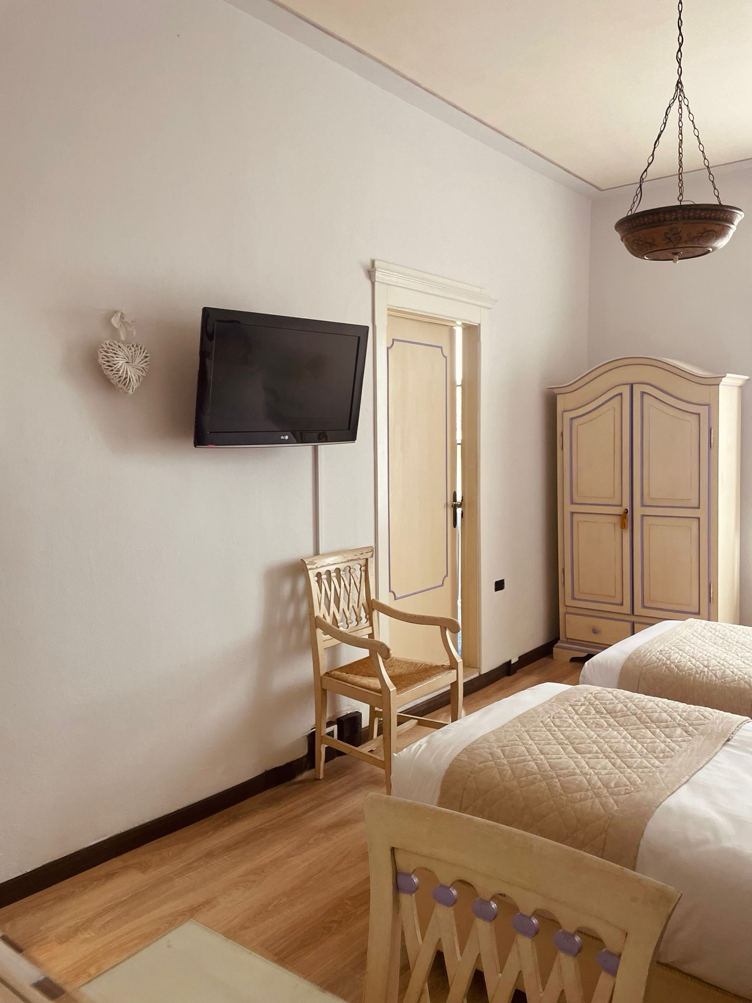 Una camera da letto con due letti, una televisione, un armadio e una sedia.