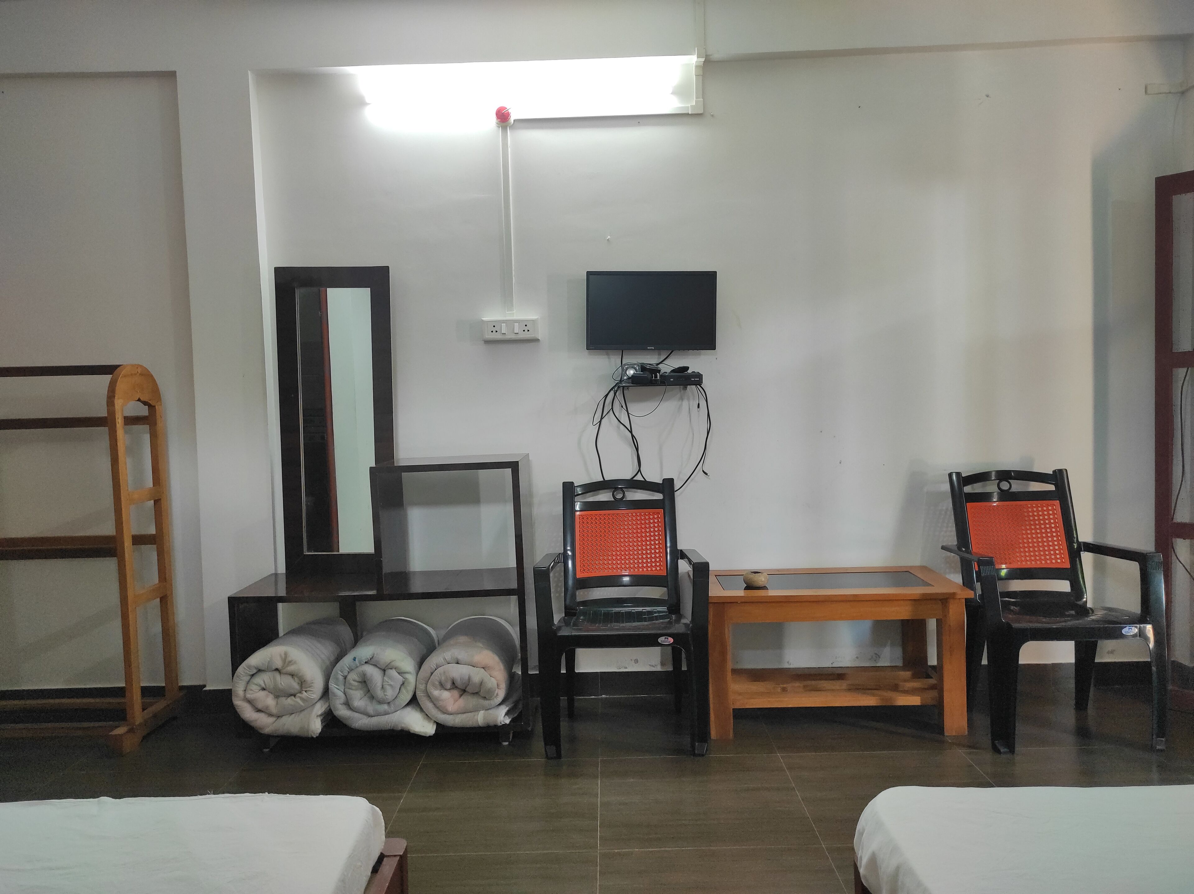 Una habitación de hotel con dos camas, un escritorio con silla, un televisor y un espejo.