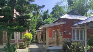 Une cour avec un bâtiment rouge, une allée couverte et de la verdure tout autour.