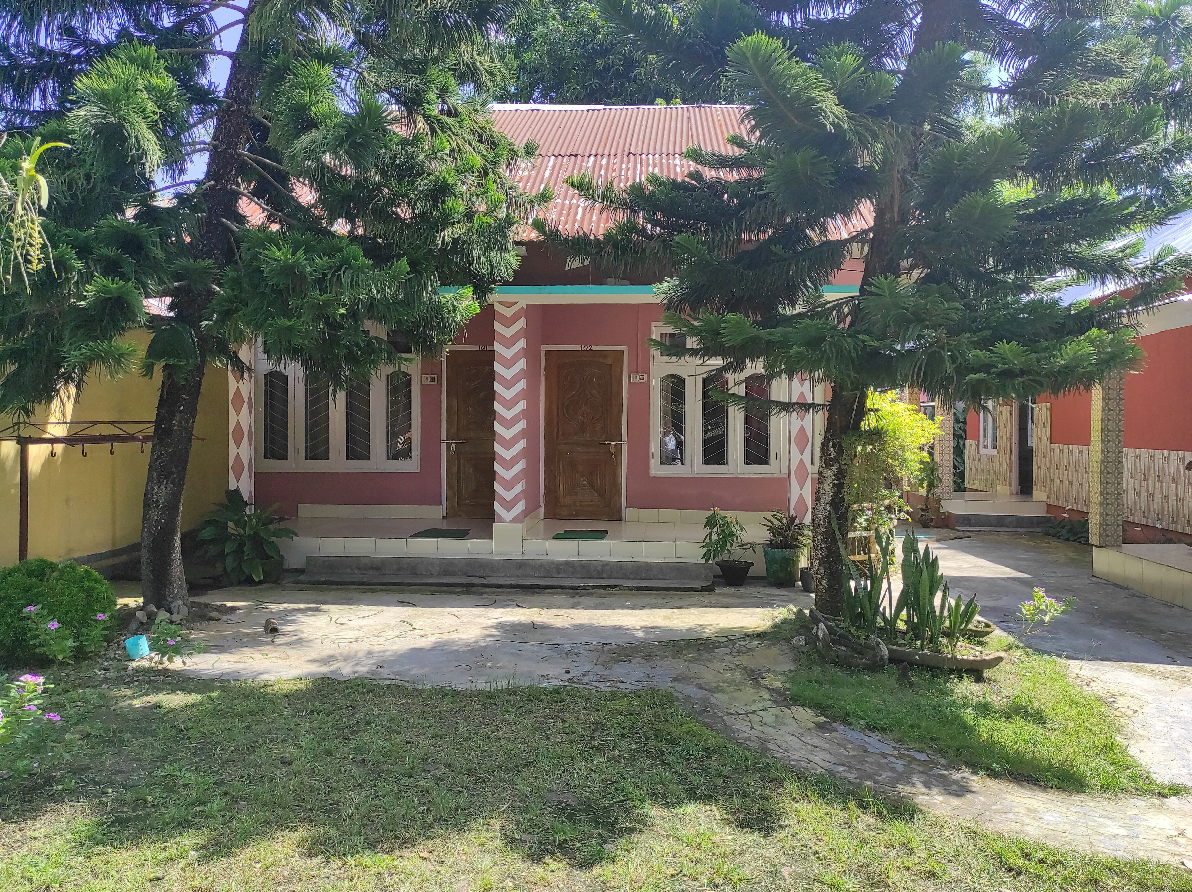 A building with a red and white facade, a central entrance with a wooden door, and a small porch area.