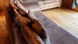 Interior acogedor de una cabaña con un sofá de cuero y techo de madera.