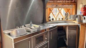 Een kleine keuken met een spoelbak, fornuis en een raam met uitzicht.