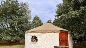 Een ronde, witte tent met een houten deur en een rond raam.