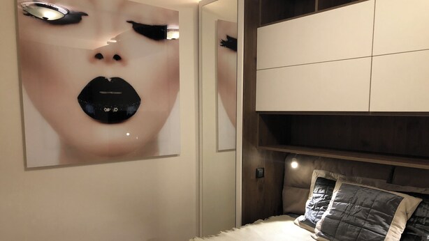 Un dormitorio con cama, cabecero y un espejo grande.