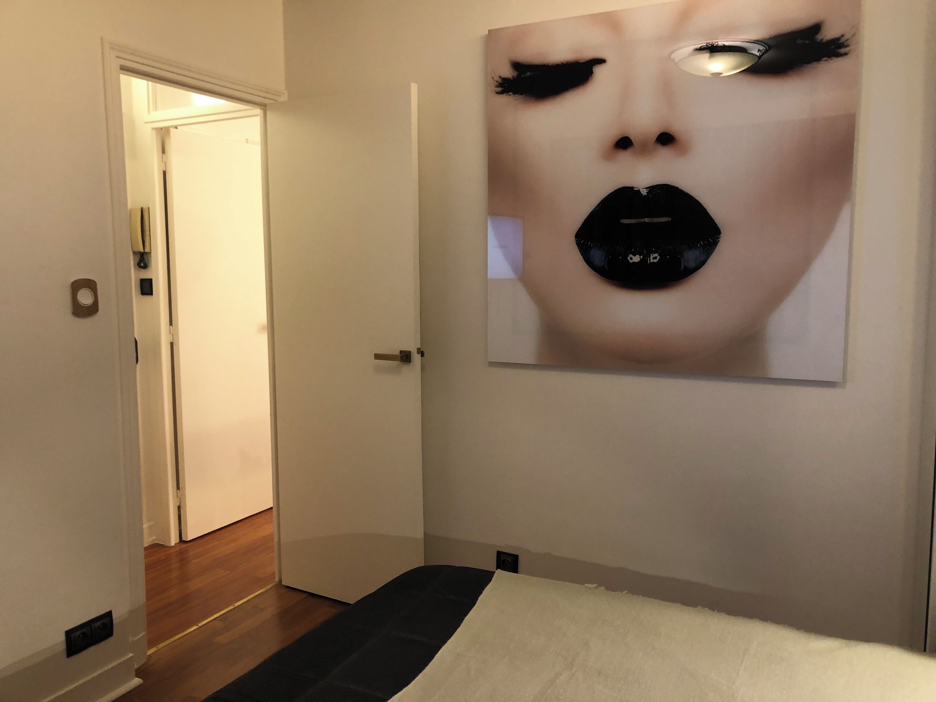 Une chambre d’hôtel avec un lit, une porte donnant sur une autre pièce et une œuvre d’art accrochée au mur.