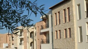 A row of residential buildings with balconies, stone facades, and arched doorways. - Modern Apartment Near the Beach in Cyprus (Polis)