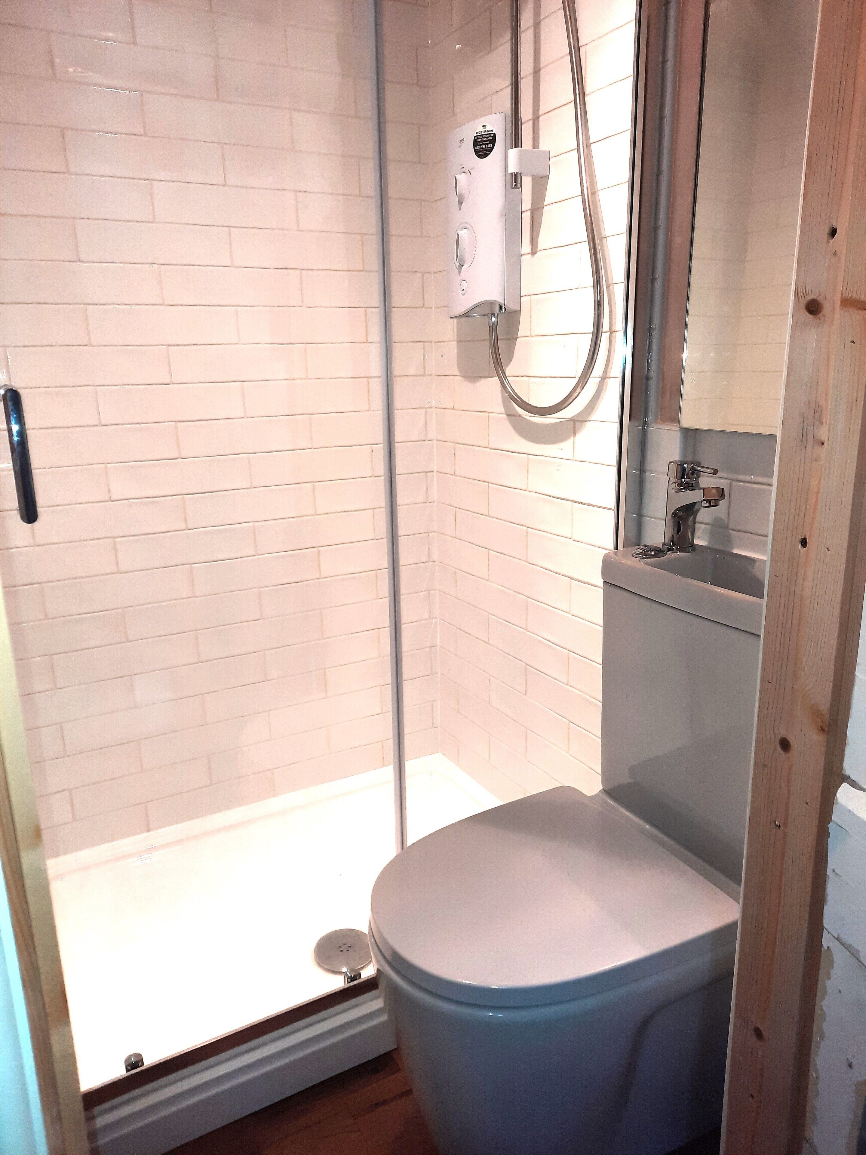 Une salle de bain avec une douche, des toilettes et un miroir.