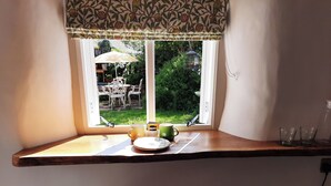 Janela de canto com vista para um pátio externo, incluindo uma mesa e cadeiras, e um comedouro para pássaros.