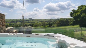 Un jacuzzi con vistas despejadas a un paisaje verde y colinas ondulantes al fondo.