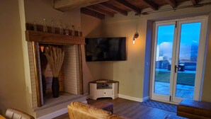 Una sala de estar acogedora con chimenea, televisor y puerta corrediza al exterior.