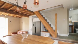 Una cocina moderna con una isla de madera, electrodomésticos de acero inoxidable y una escalera que sube a otro nivel.