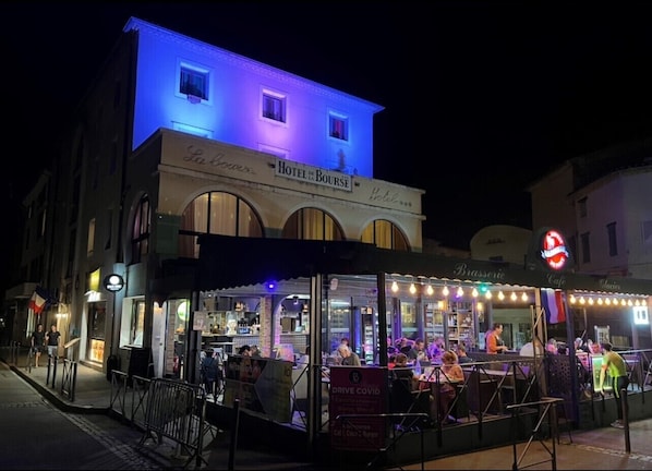 A hotel named "Hotel de Bourse" with outdoor seating and a visible sign indicating "Drive COVID".