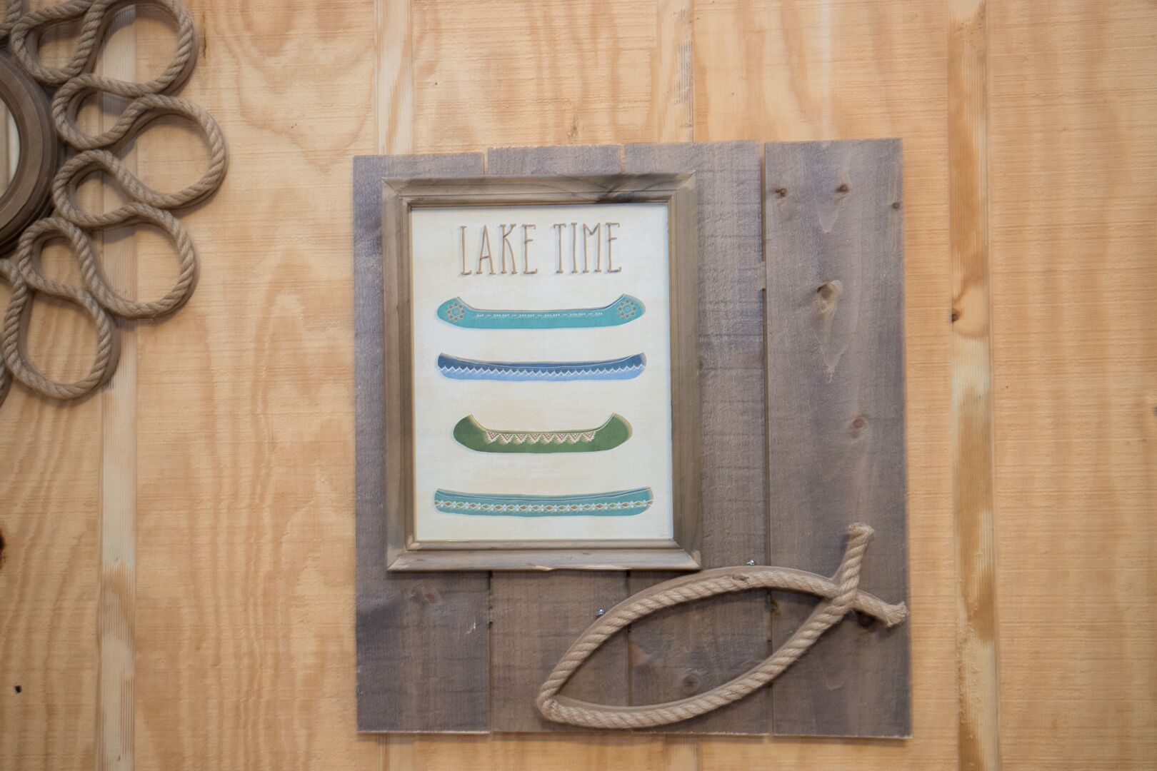 En trævæg med et rammet skilt, der siger "LAKE TIME", og billeder af kanoer.