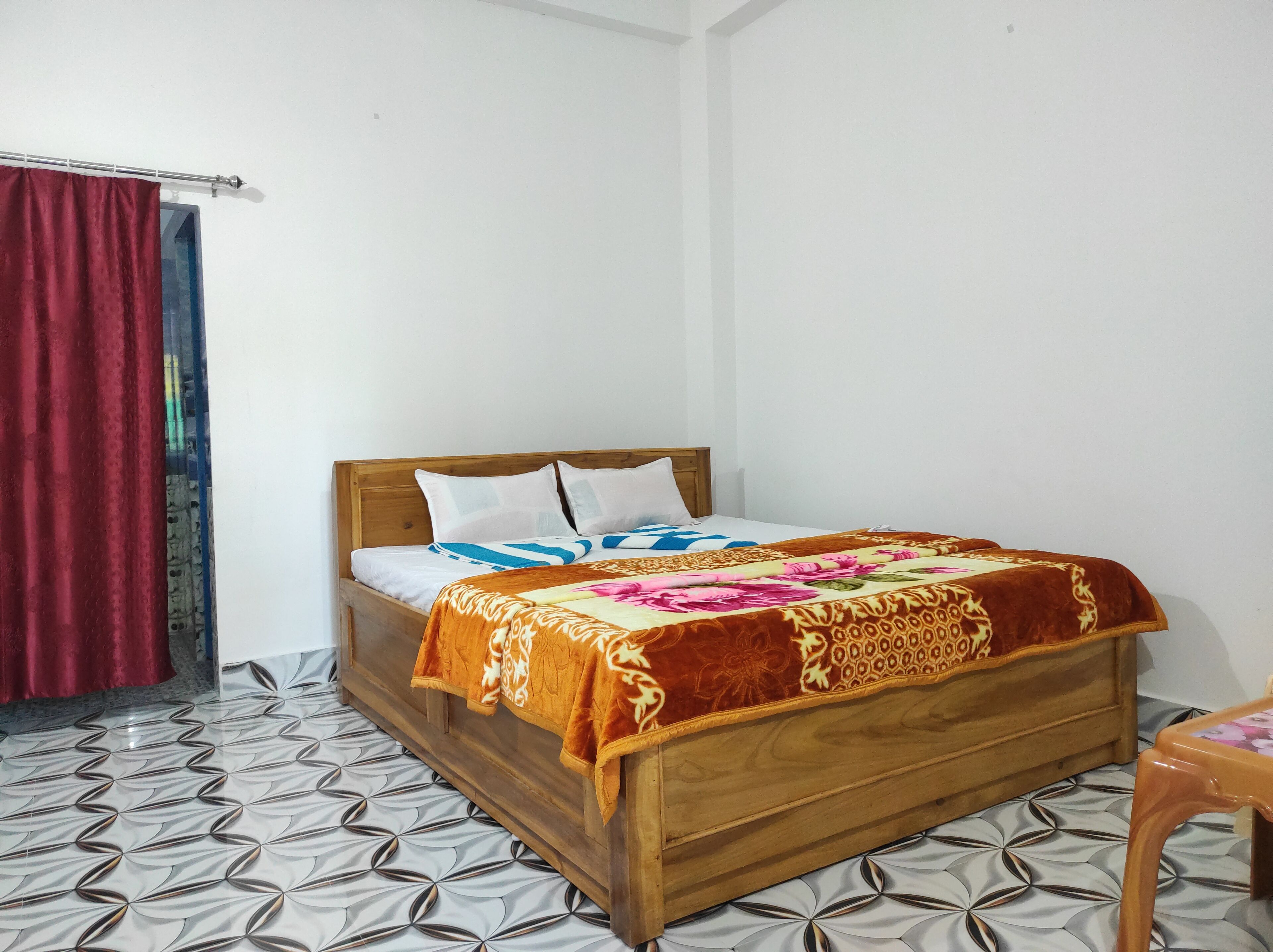 Uma cama de solteiro com cabeceira de madeira, roupa de cama branca e um cobertor estampado com motivos florais.