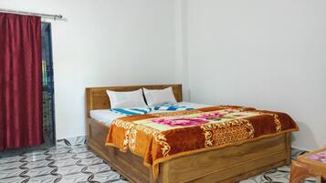 Uma cama de solteiro com cabeceira de madeira, roupa de cama branca e um cobertor estampado com motivos florais.