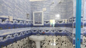 A bathroom with a sink, mirror, and blue wave-patterned walls. - Homecation Manas River Rock Lodge (Barnagar)