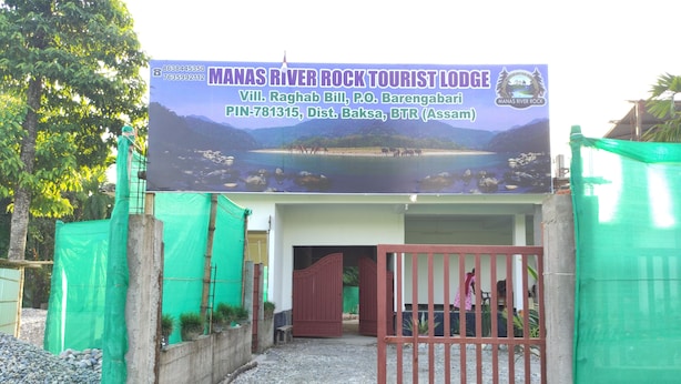 A sign for Manas River Rock Tourist Lodge with contact numbers and location details. - Homecation Manas River Rock Lodge (Barnagar)