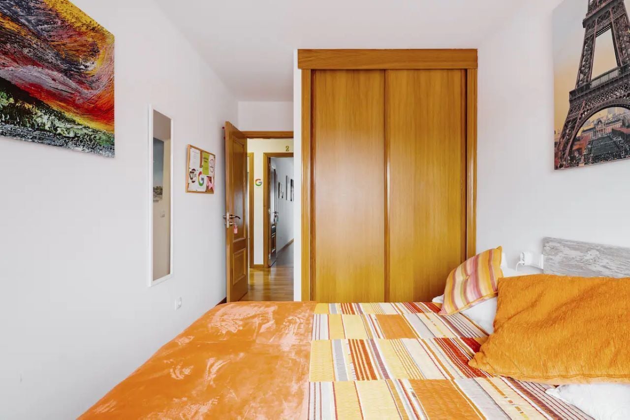 Een slaapkamer met een bed, een houten garderobe en een schilderij van de Eiffeltoren.