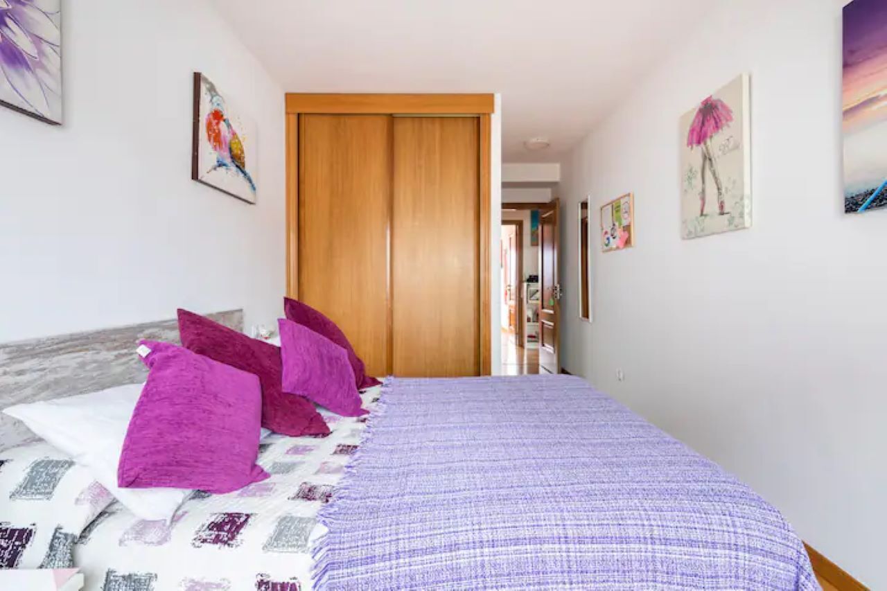 A bedroom with a bed, pillows, and artwork on the walls.