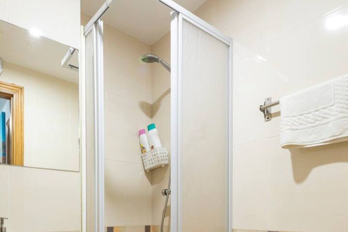 A bathroom with a glass-enclosed shower, a toilet, and a sink.