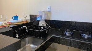 A compact kitchen with a sink, a blender, a stove, and a countertop.