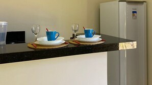 A kitchen with a black countertop, a stainless steel refrigerator, and two blue cups on white saucers.