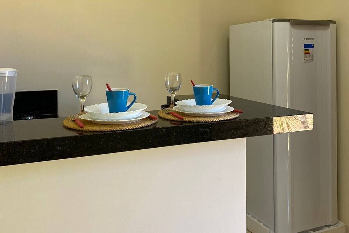 Eine Küche mit schwarzer Arbeitsplatte, einem Edelstahl-Kühlschrank und zwei blauen Tassen auf weißen Untertassen.