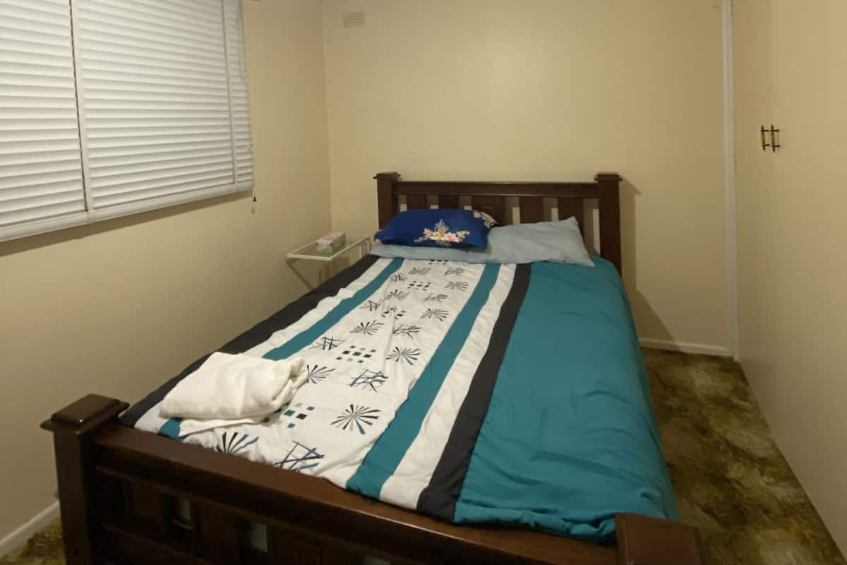 A bedroom with a wooden bed, a nightstand, a ceiling fan, and a window with blinds.