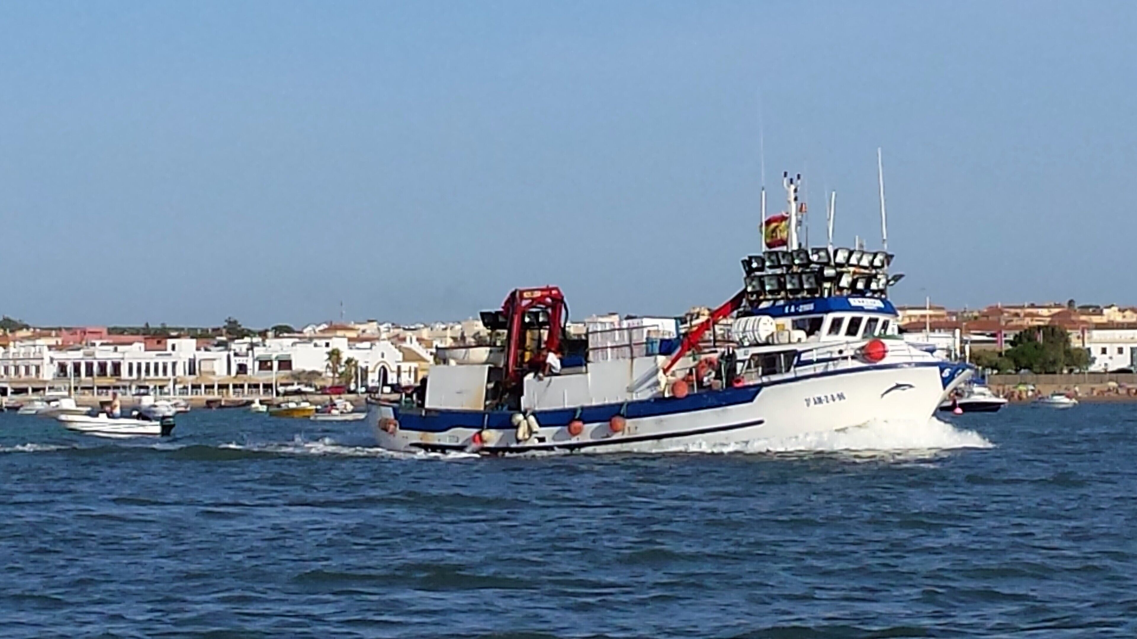 Un bateau aux couleurs bleu et blanc, doté d’une cabine et d’un drapeau au sommet.